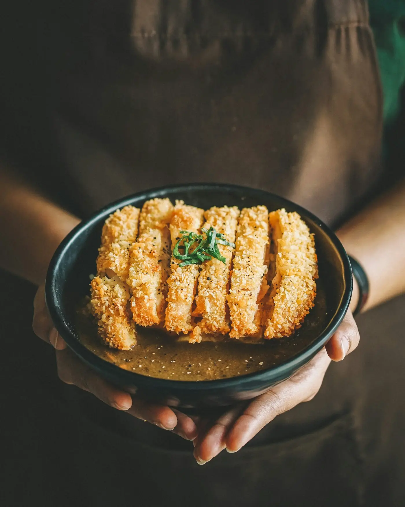 Tranches de viande panée sur une assiette noire