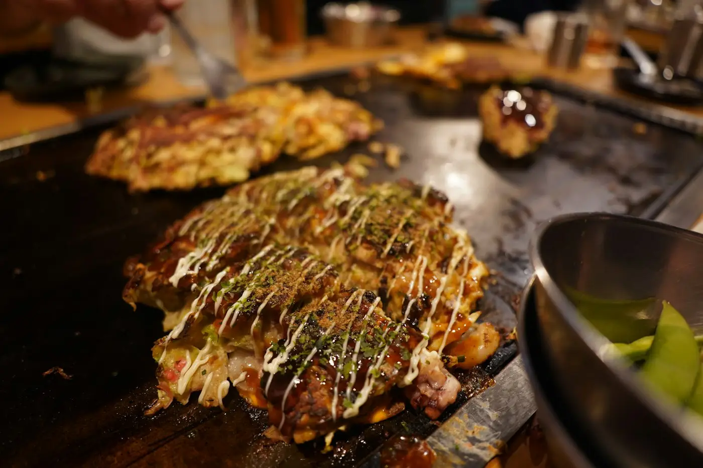 Un okonomiyaki en train de cuire sur une plaque chauffante