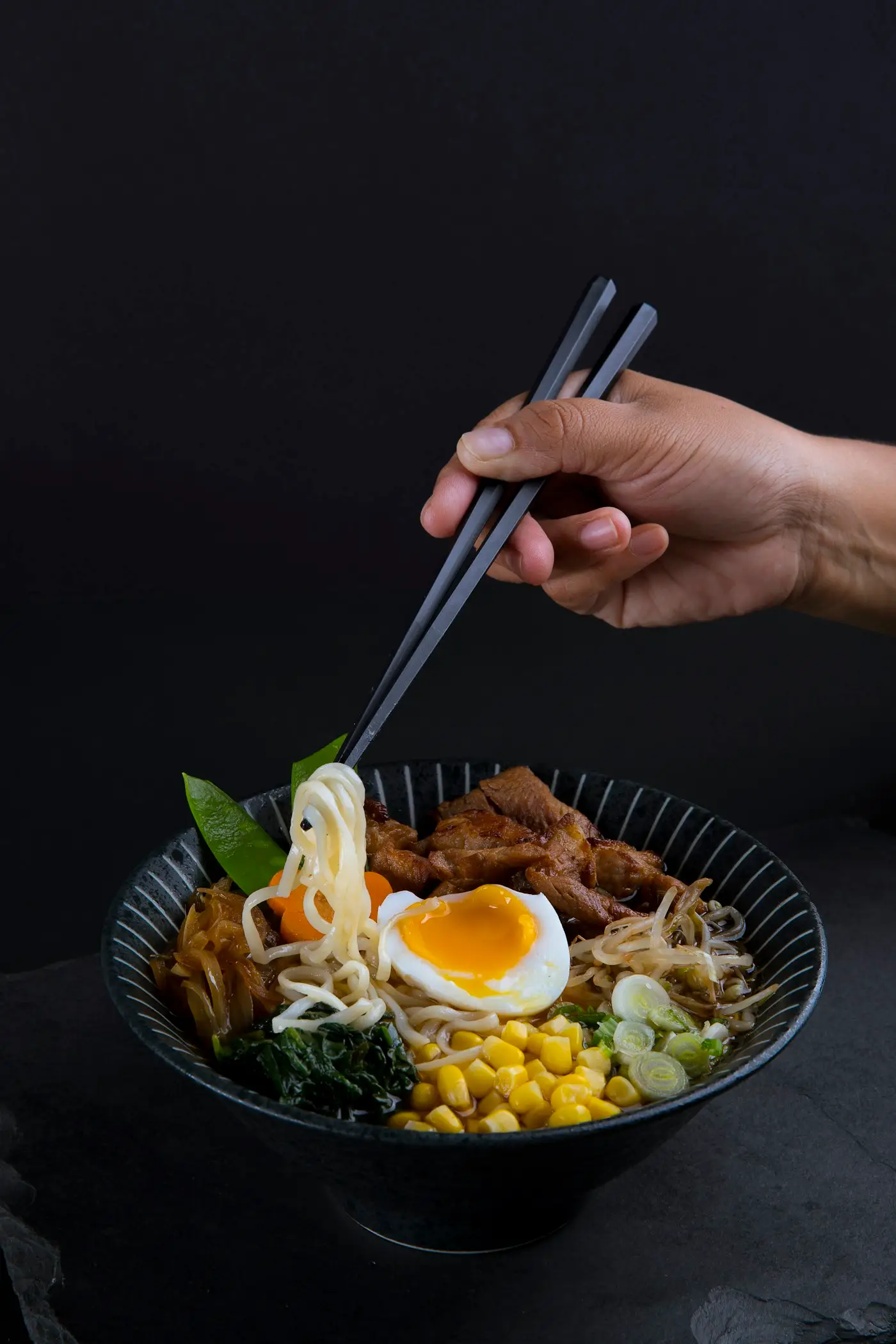 Des baguettes soulèvent des nouilles de ramen