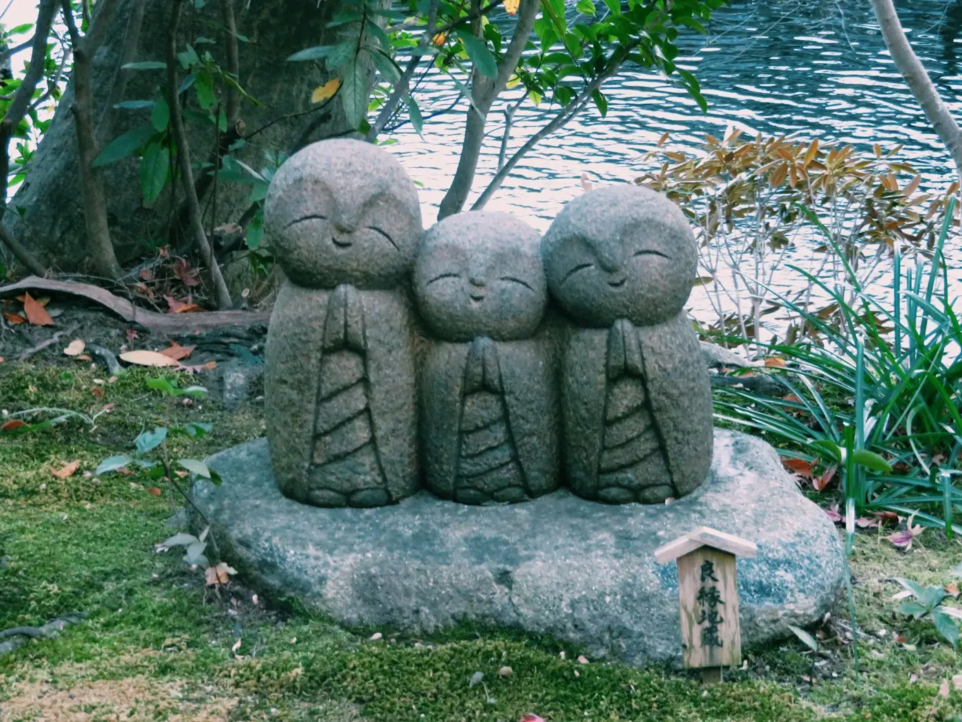 Trois petites statues de Jizō sur un rocher couvert de mousse