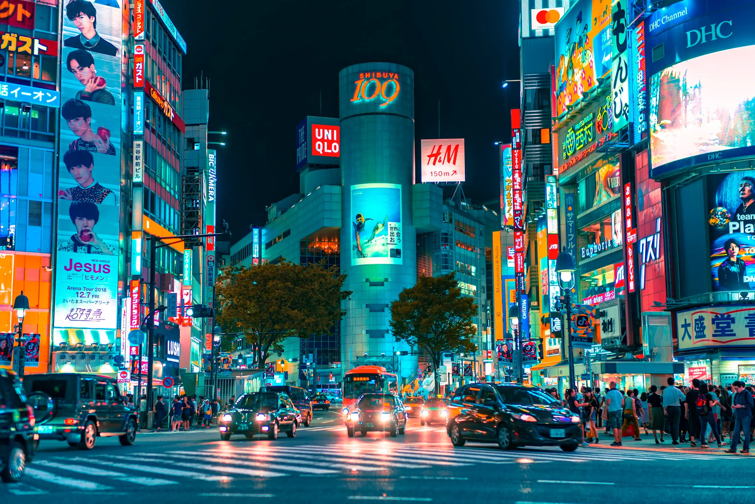 Le carrefour de Shibuya de nuit, entouré d'écrans lumineux