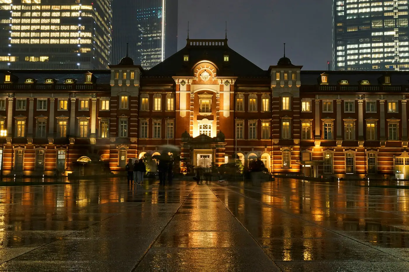 La gare de Tokyo et sa façade de briques illuminée, un soir de pluie